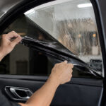 Installer removing old window film from a car window
