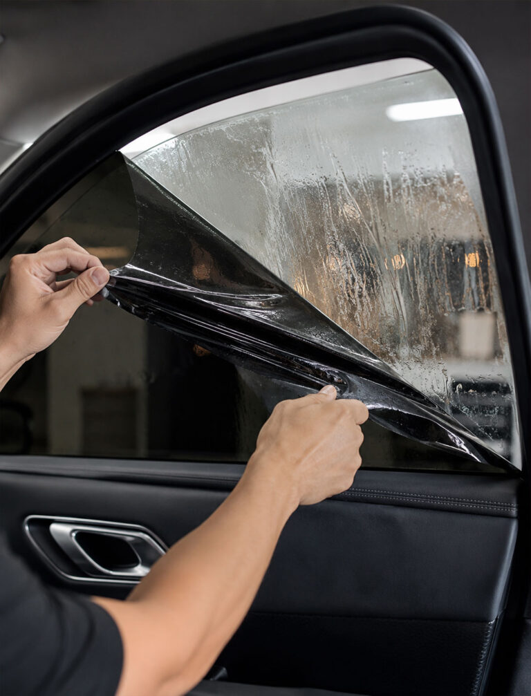 Installer removing old window film from a car window